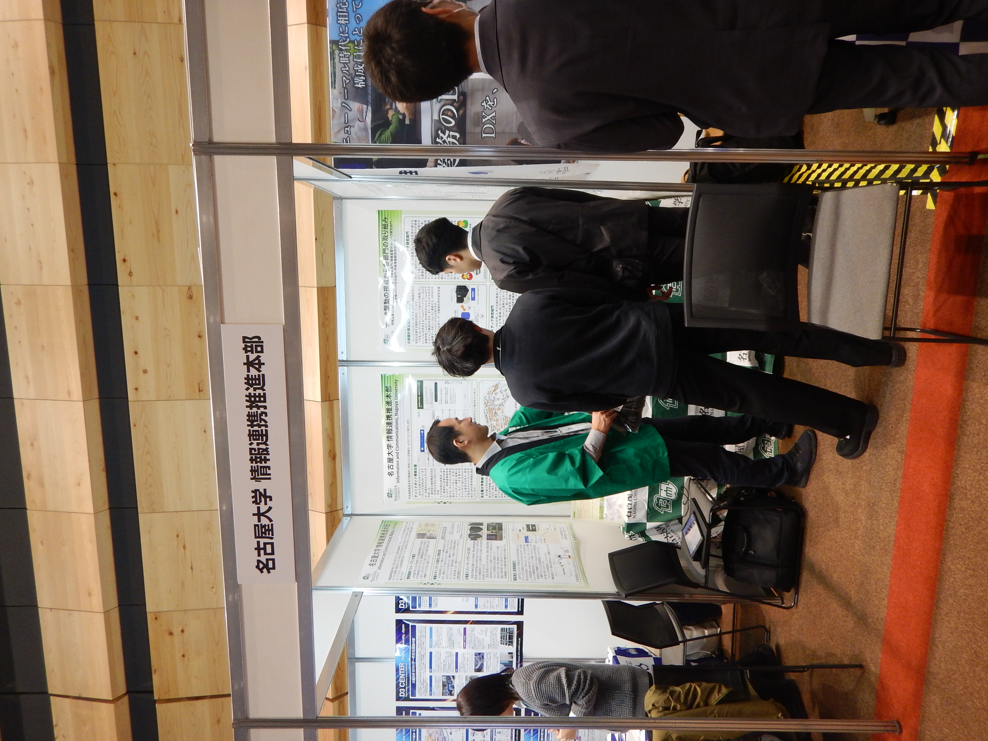 図1: 情報基盤センターのロゴの入った法被を来た展示員と来訪者