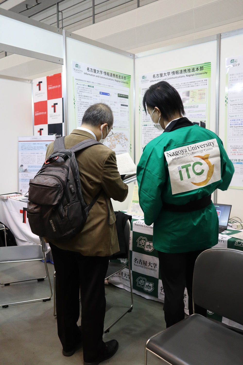 図2: 情報基盤センターのロゴの入った法被を来た展示員と来訪者